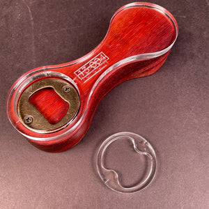 curvy infinity ring that is blocked out on a bright red piece of wood. The shape almost looks like two cricles that are being connected my a skinny rectangle that is curvy and will feel nice in the consumers hand.n Looks like a peanut 
